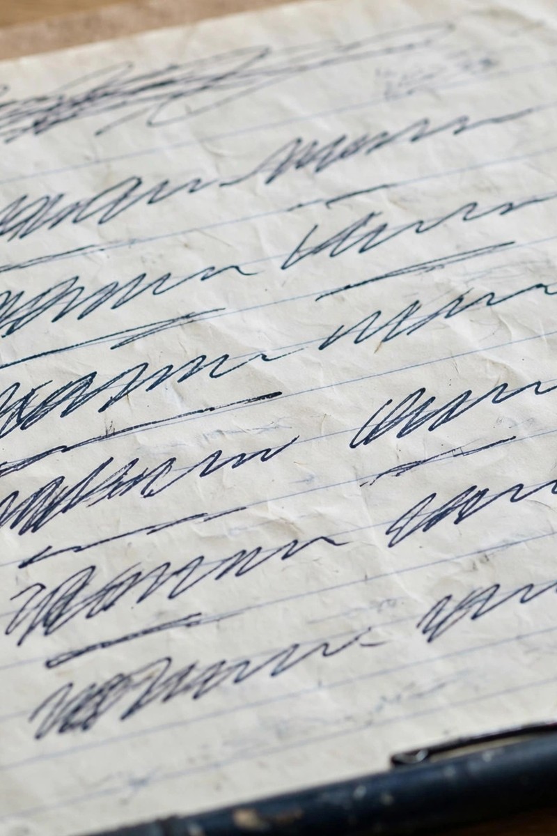 Close-up of a handwritten list in a notebook with a pen resting beside it.